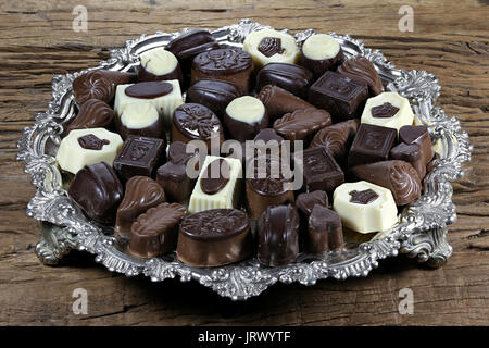 Vassoio in argento con belga praline di cioccolato su rustico sfondo di legno Foto Stock