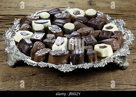 Vassoio in argento con belga praline di cioccolato su rustico sfondo di legno Foto Stock