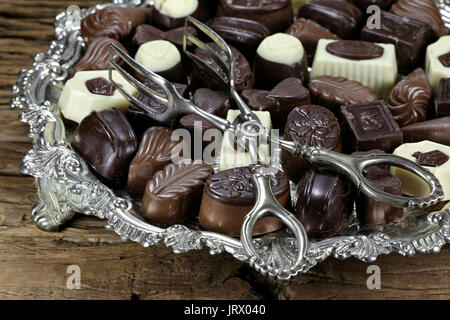 Vassoio in argento con belga praline di cioccolato su rustico sfondo di legno Foto Stock