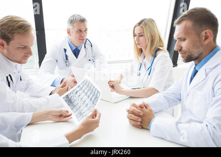 Team di medici che lavorano in ufficio a discutere di cervello MRI scan Foto Stock