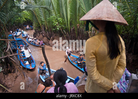 Donna e barche a remi sul fiume Mekong, vicino a My Tho village, Vietnam. Bao Dinh canale, delta del Mekong. La donna a non conica hat canottaggio una piccola barca su Foto Stock