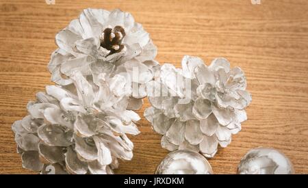 Ornamenti natale, Baubles e pigne nelle quali sulla tavola di legno, segno per la celebrazione del Natale. Foto Stock