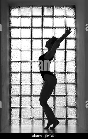 Donna di silhouette con finestra sullo sfondo nei toni del bianco e del nero Foto Stock