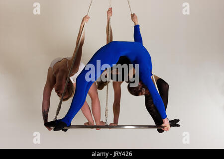 Giovane donna di trio facendo som acrobatici volteggi sull'antenna di lucentezza Foto Stock