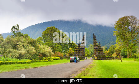 Simbolo tradizionale di isola tropicale bali: pittoresco arco in stile induista con la strada che conduce al tempio contro lo sfondo della montagna Foto Stock