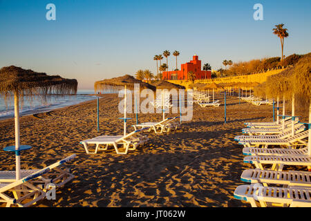 Spiaggia amache di sunrise. Bil-Bil castello costruito in stile neo-stile Arabo nel 1934, Benalmadena. Provincia di Malaga Costa del Sol. Andalusia Spagna meridionale, Europ Foto Stock