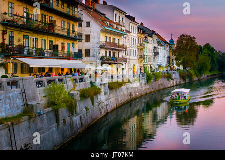 Panorama della città vecchia di Lubiana, Slovenia, con numerosi bar e ristoranti con vista sul porto di fiume Ljubljanica nel tramonto, panorama barca sul fiume, clo Foto Stock