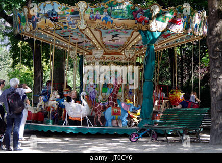 Bambini che viaggiano su una piccola giostra, Square des Batignolles Parigi Francia, mentre i genitori e i nonni troppo, ammirare e fotografare. Foto Stock