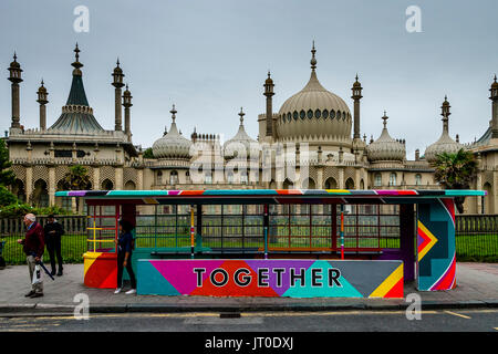 Le persone in attesa di un autobus in una maniera colorata Bus verniciato Shelter, Brighton, Sussex, Regno Unito Foto Stock