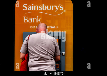 Un uomo si ritira contanti da un ATM, Brighton, Sussex, Regno Unito Foto Stock