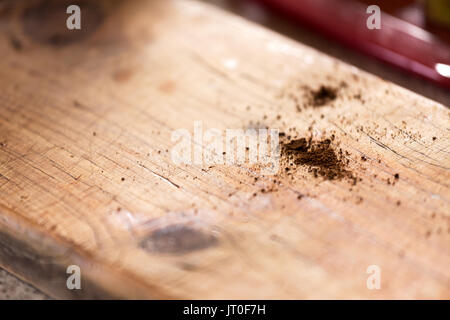 Un abstract close up di caffè macina versato su di un legno rustico cafe banco con profondità di campo e spazio per il testo o il contenuto. Foto Stock