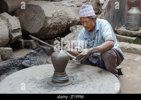 Potter funzionamento manuale di una mola di pietra in ceramica quadrata, Bhaktapur, Nepal. Foto Stock