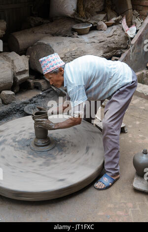 Potter funzionamento manuale di una mola di pietra in ceramica quadrata, Bhaktapur, Nepal. Foto Stock