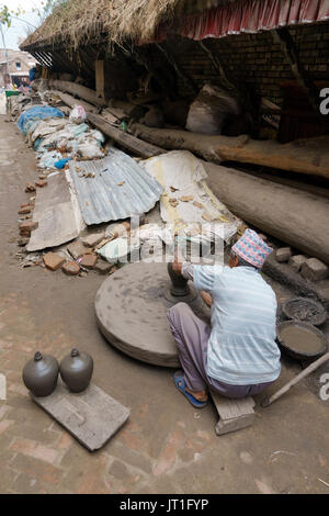 Potter funzionamento manuale di una mola di pietra in ceramica quadrata, Bhaktapur, Nepal. Foto Stock