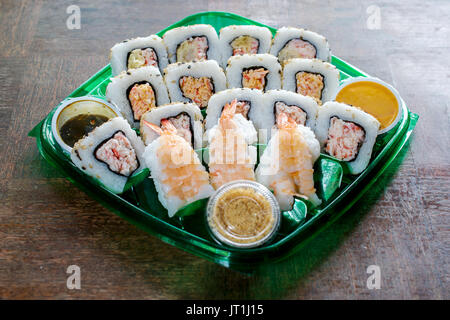 Collocato verticalmente il sushi di gamberi e rotoli venduti a effettuare la scatola sul tavolo in legno- Oriental fast-food concept Foto Stock