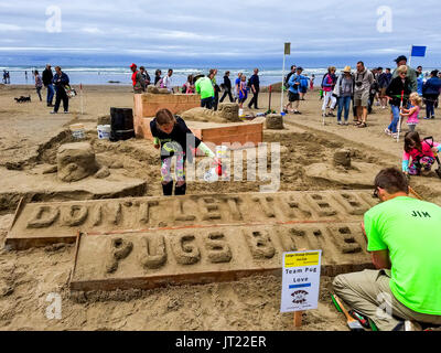 Sandcastle Contest lungo Cannon Beach in Oregon, USA. Le squadre competono per scolpire le scene elaborate di sabbia. Team vincente funziona su Safari di retromarcia Foto Stock