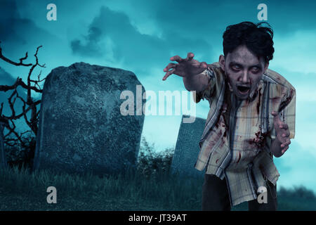 Orribili zombie asiatici uomo in vestiti in piedi sul cimitero Foto Stock