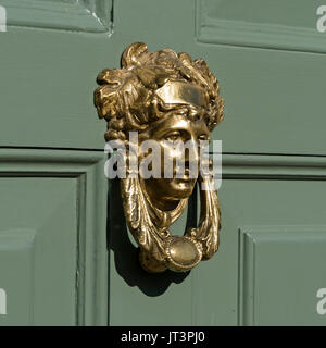 Smart golden ottone lucidato porta respingente raffigurante la dea romana Apollo, sul dipinto di verde con pannelli in legno porta anteriore. Foto Stock