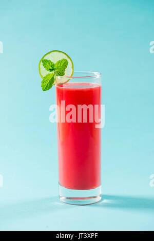 Bicchiere di sano succo di anguria in estate su sfondo blu. Foto Stock