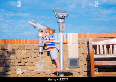 Bambino guarda attraverso il telescopio sulla giornata di sole in estate, vacanze scena Foto Stock