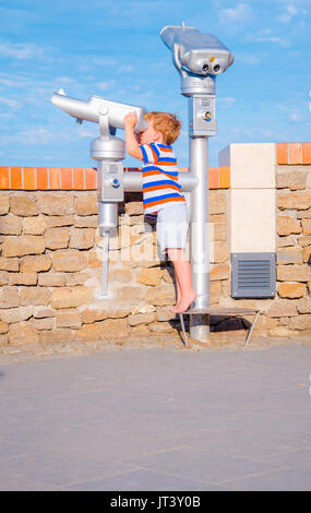 Bambino guarda attraverso il telescopio sulla giornata di sole in estate, vacanze scena Foto Stock