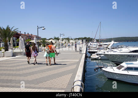 I turisti di passeggiare lungo la passeggiata a fianco della zona di Marina in Medulin, Croazia sulla Riviera istriana Foto Stock