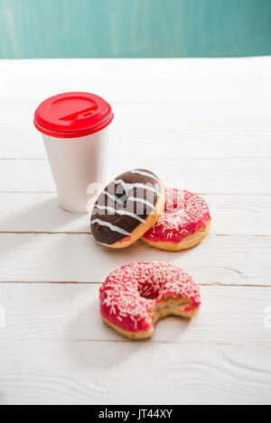 Angolo di Alta Vista della tazza di caffè e ciambelle tre con cioccolato e lamponi glassa. ciambelle e concetto di caffè Foto Stock