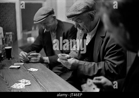 Uomini di gruppo della costa occidentale dell'Irlanda che giocano a carte seduti al bar in un pub del villaggio, comunità di amicizia Contea Kerry Irlanda del Sud Eire 1969 1960s HOMER SYKES Foto Stock