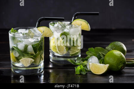 Vista ravvicinata di cocktail mojito in bicchieri, menta e limes sul nero, cocktail bevande concept Foto Stock