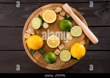 Vista dall'alto di limoni e limette con lo zucchero di canna sulla cucina in legno bordo, barman cocktail Foto Stock