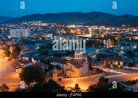 Gori, Shida Kartli Regione, Georgia. Gori Cityscape di illuminazione serale sotto il cielo blu nel crepuscolo. Cattedrale della Beata Vergine Maria nella notte ho Foto Stock