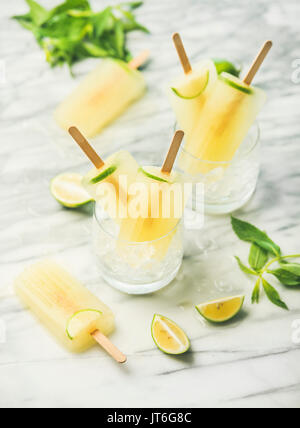 Estate rinfrescante limonata popsicles con lime e menta in bicchieri con scaglie di ghiaccio, il fuoco selettivo Foto Stock
