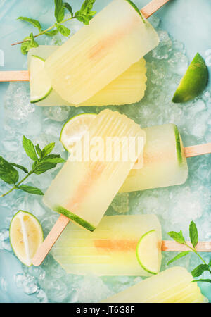 Estate rinfrescante limonata popsicles con lime e menta con scaglie di ghiaccio su sfondo blu, vista dall'alto Foto Stock