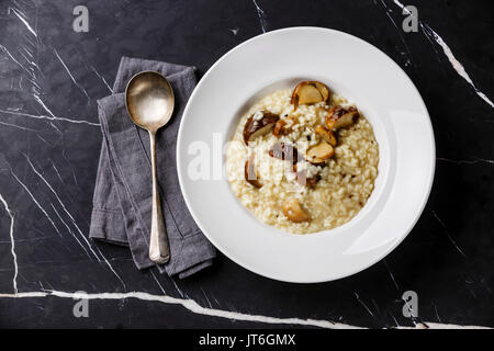 Risotto con funghi porcini su piastra in marmo scuro dello sfondo della tabella Foto Stock