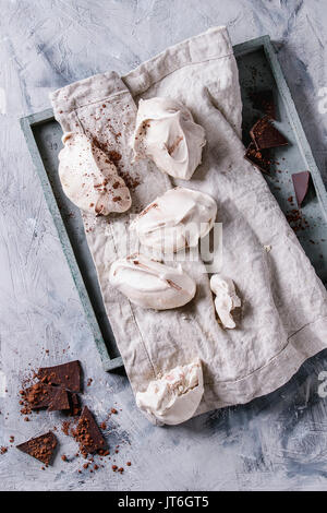La cottura in casa francese dessert meringa con cioccolato servito con spacco scuro cioccolato e cacao in polvere sul tessile igienico vassoio in legno su grigio co Foto Stock