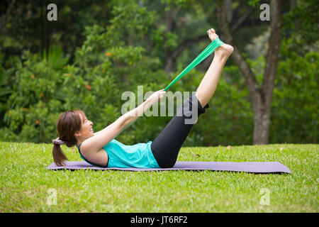 Athletic donna asiatica esercizio con una banda di resistenza. Azione e uno stile di vita sano concetto. Foto Stock