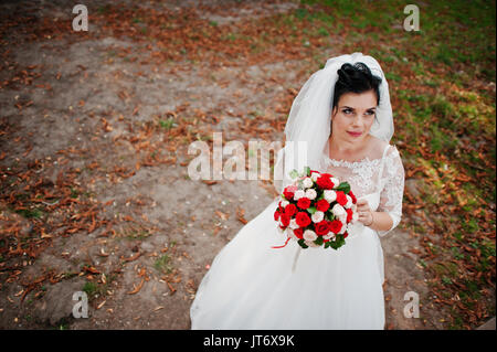 Ritratto di una fantastica sposa indossando splendidi abiti da sposa e velo pone con un bouquet. Foto Stock