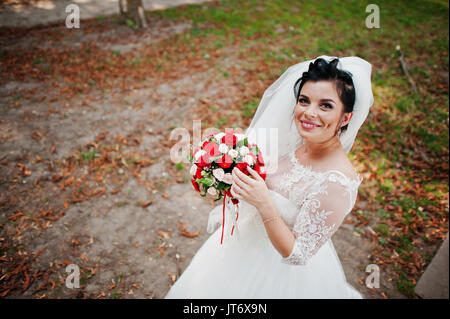 Ritratto di una fantastica sposa indossando splendidi abiti da sposa e velo pone con un bouquet. Foto Stock