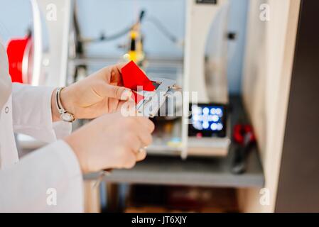 Donna verificando le dimensioni del componente realizzato nella stampante 3d dalla pinza. Controllo di qualità Foto Stock