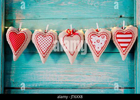 Cuori di tessili sul vecchio turchese rustico in legno sfondo. Il giorno di San Valentino Foto Stock