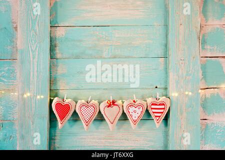 Cuori di tessili sul vecchio turchese rustico in legno sfondo. Il giorno di San Valentino Foto Stock