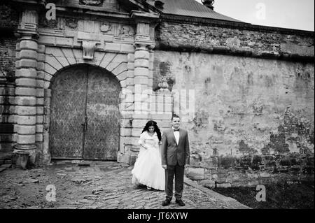 Incredibile sposi in posa vicino alle antiche porte di un castello. Foto in bianco e nero. Foto Stock