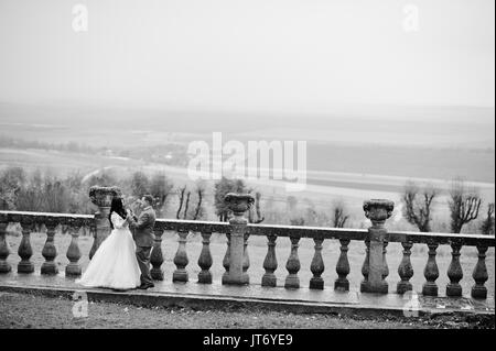 Fantastico matrimonio giovane in piedi sulla terrazza con una vista del paesaggio circostante. Foto in bianco e nero. Foto Stock