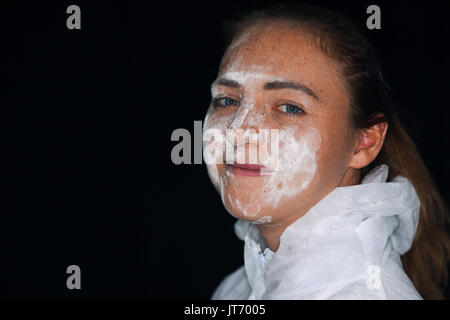 Un giovane lavoratore di sesso femminile che indossa un monouso tuta antipolvere Foto Stock