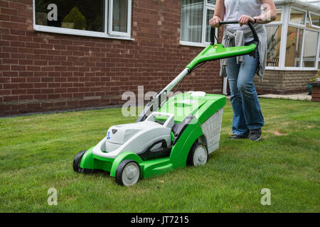 Un casualmente vestito donna Falciare il prato con un VIKING MA339C Tosaerba cordless. Candide. Estate, UK. Foto Stock