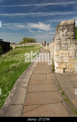 Antico muro romano con la gente in la distanza a piedi su immensa struttura sotto il cielo blu alla storica città di York, Inghilterra Foto Stock