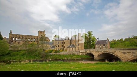 Vista panoramica di imponenti rovine di Jedburgh Abbey e gli edifici della città vecchia al di là di Jed acqua del fiume e ponte arcuato, Scozia Foto Stock