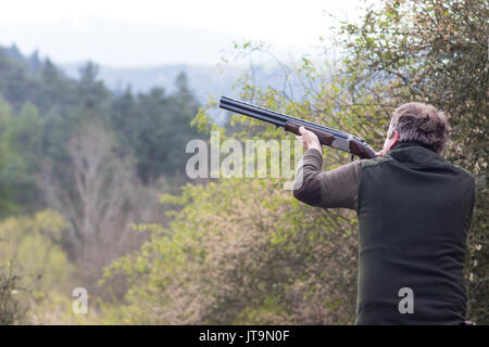 Hunter nel bosco durante la stagione di caccia mirando prima di sparare Foto Stock