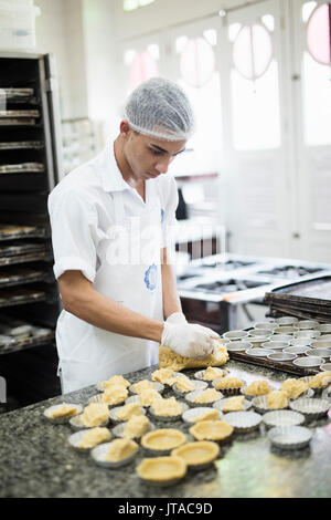 Un baker rendendo portoghese crostate di crema pasticcera in Confeitaria Colombo, una famosa caffetteria nel centro di Rio de Janeiro, Brasile, Sud America Foto Stock