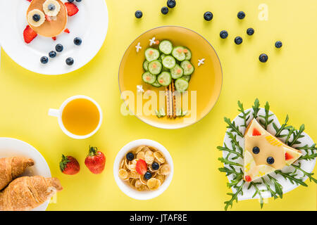 Vista dall'alto di stile in modo creativo i bambini della prima colazione con croissant e succhi di frutta Foto Stock